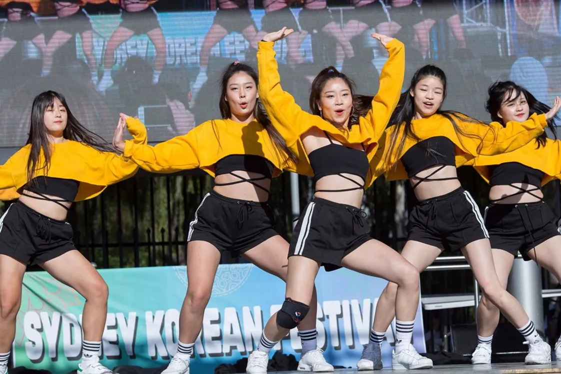 Four Korean female dancers performing a K-pop-style dance routine on stage