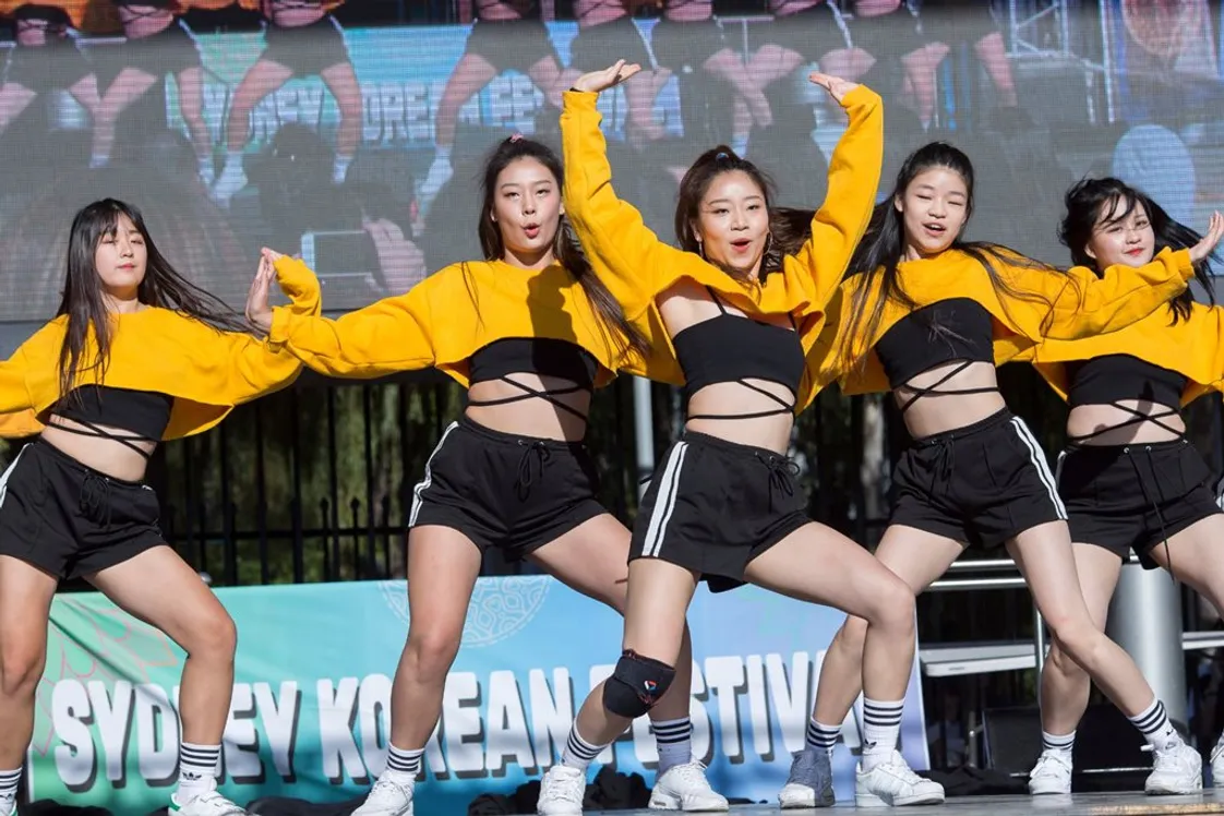 Four Korean female dancers performing a K-pop-style dance routine on stage